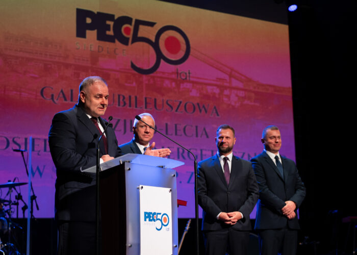 Przemowa Przewodniczącego Rady Miasta Siedlce Roberta Chojeckiego podczas gali jubileuszowej, w tle Prezydent Miasta Siedlce oraz Zarząd Przedsiębiorstwa Energetycznego w Siedlcach Sp. z o.o.